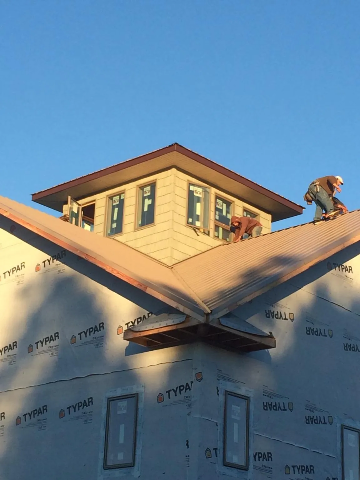 Roofers working around a rooftop cupola on a new metal roof at sunset — Roof Waterproofing in Lafayette by Roofing Brothers